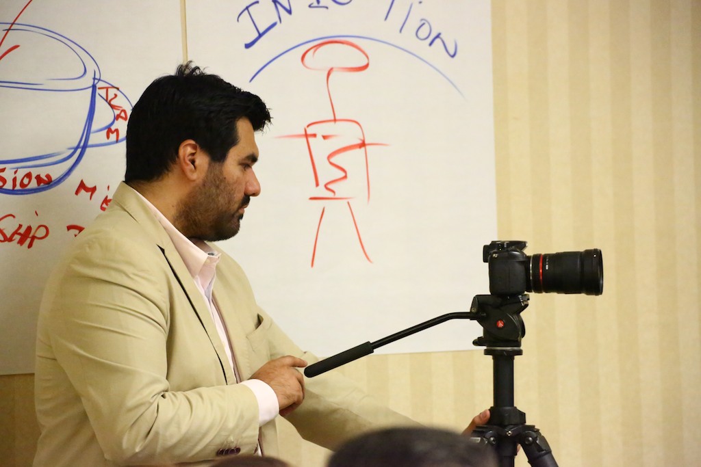 Steve Lemus operating a camera while filming a whiteboard training session